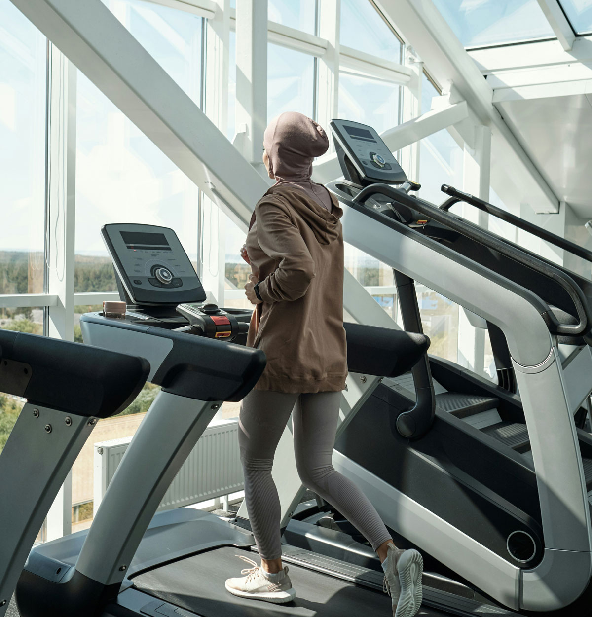 Woman running on treadmill in a gym, looking out of the window